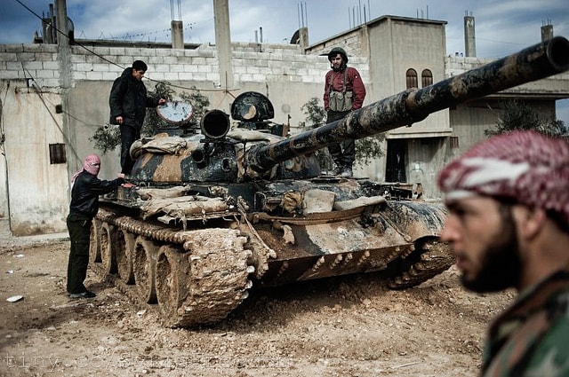 Free Syria Army members pose beside an abandoned tank. The Syrian opposition and Western powers insist that Syrian President Assad steps down from power. Photo courtesy of Freedom House.