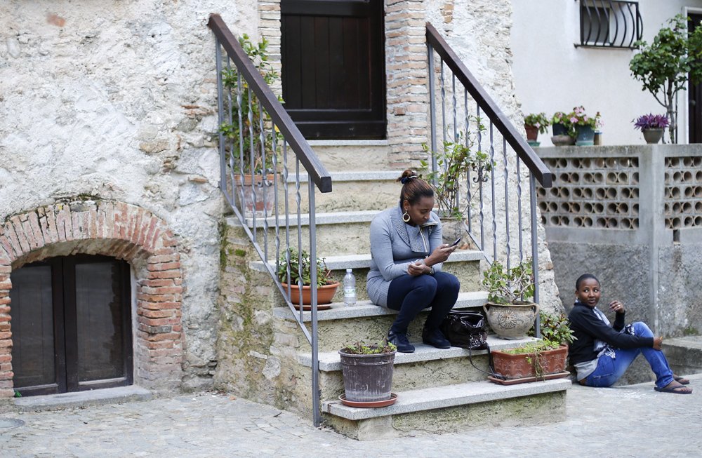 Two women talk as they sit in Riace