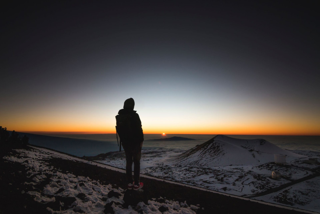 Hiker facing the expansive horizon in Mauna Kea, U.S