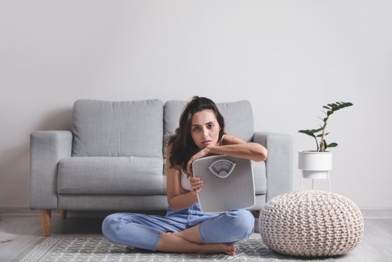 Woman holding a weight scale.