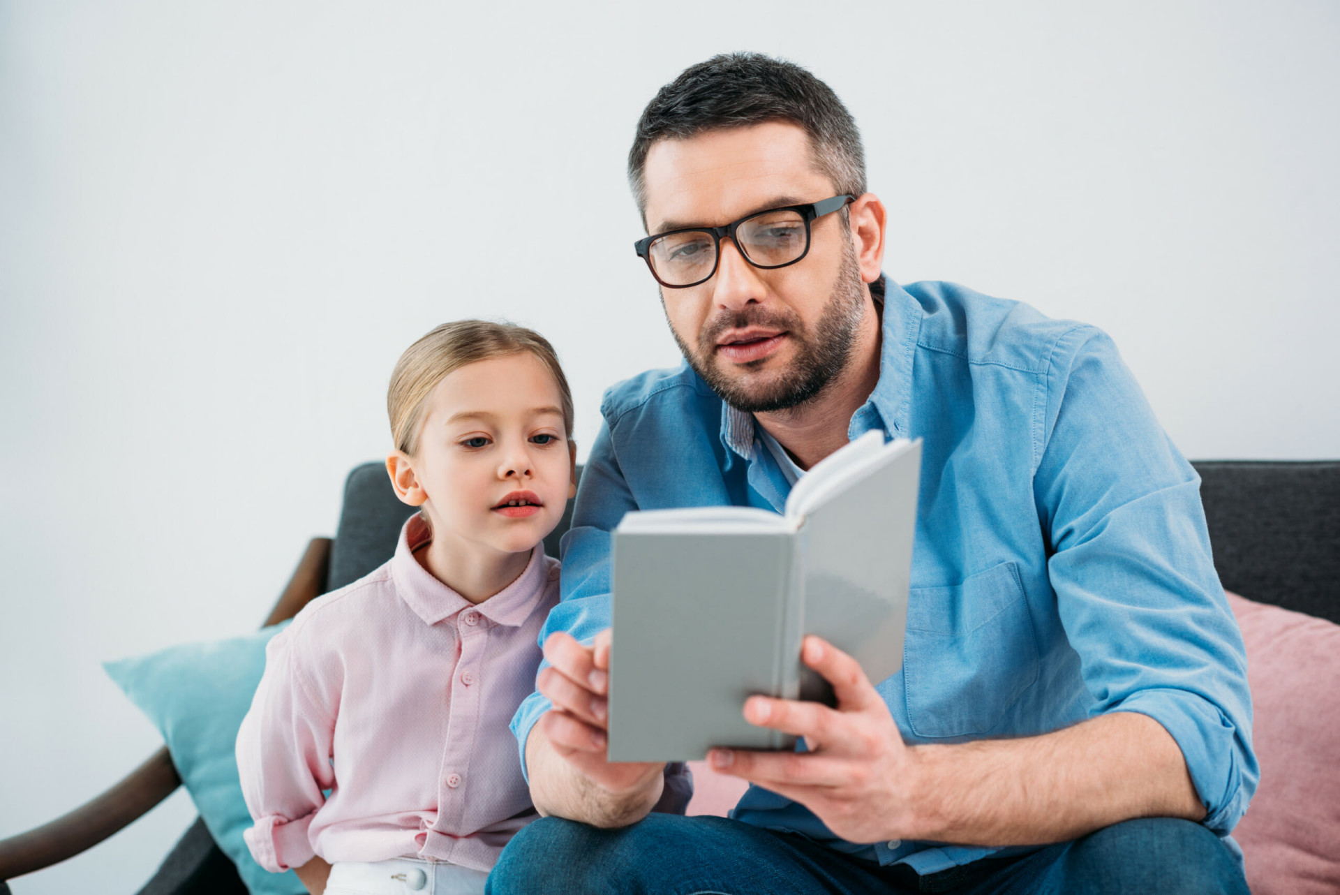 Portrait of father and daughter reading book together at home