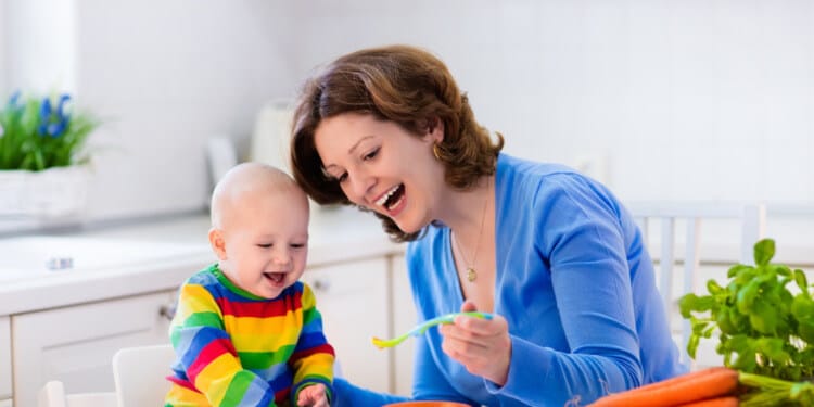 Mother feeding baby with carrots