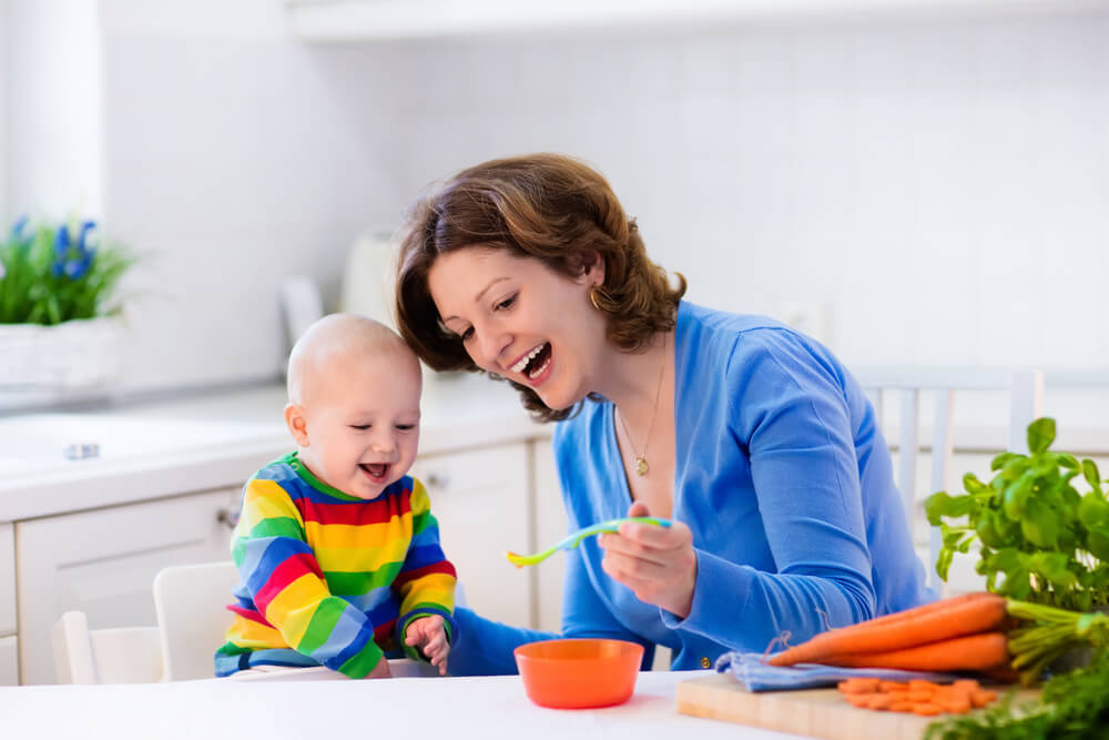 Mother feeding baby with carrots
