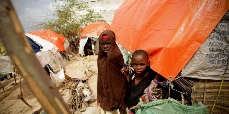 In the Photo: Somali children stand at a camp for Internally Displaced Persons (IDPs) in Mogadishu.  Somalia is affected by a severe drought that has ravaged large swaths of the Horn of Africa, leaving an estimated 22 million people in need of humanitarian assistance. Photo Credit: UN.