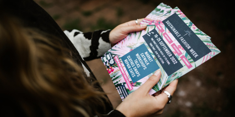 Woman holding Sustainable Fashion Week Leaflets.