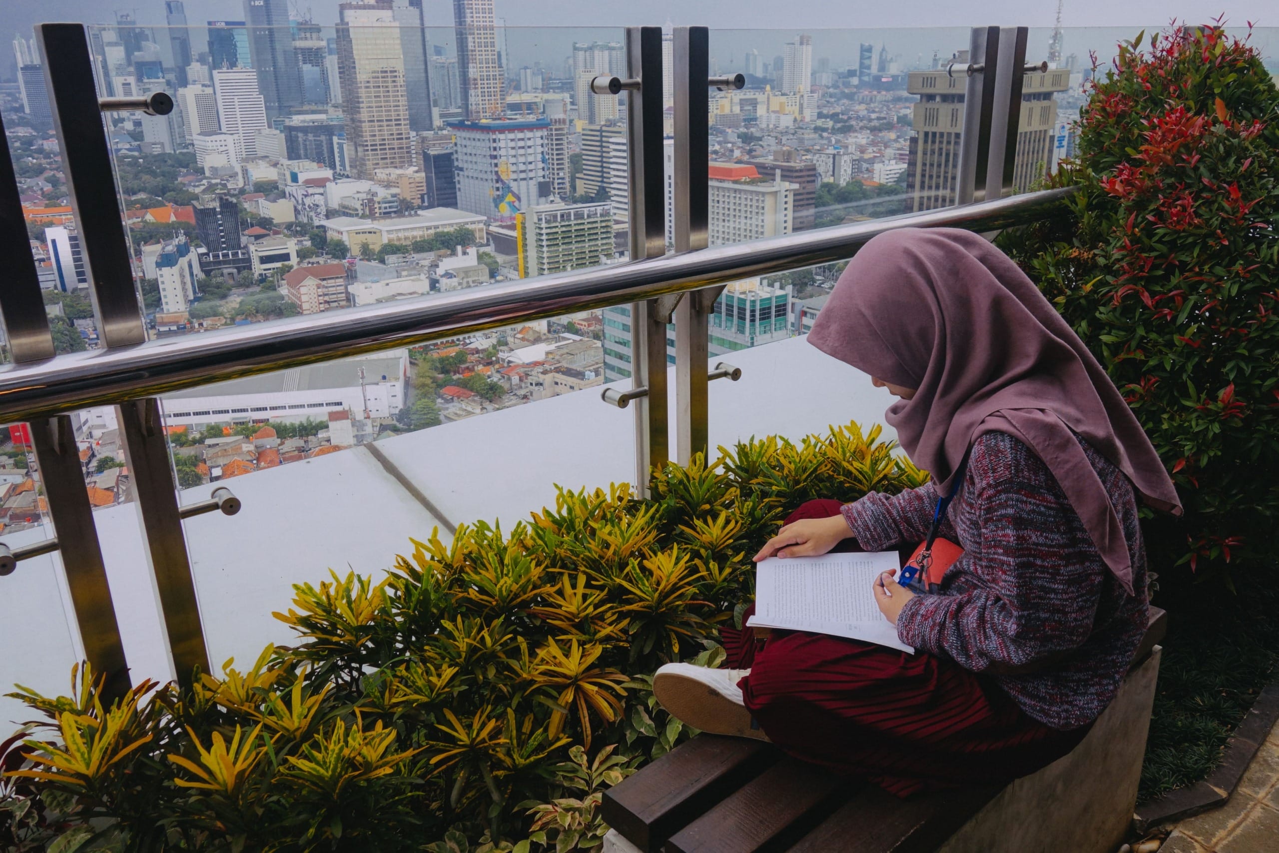 Vertical Villages: A girl sits and reads above Jakarta's skyline