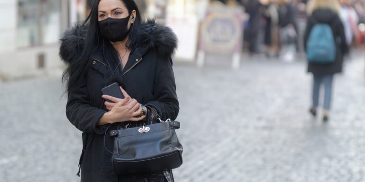 A woman in urban streetwear walks on a street.