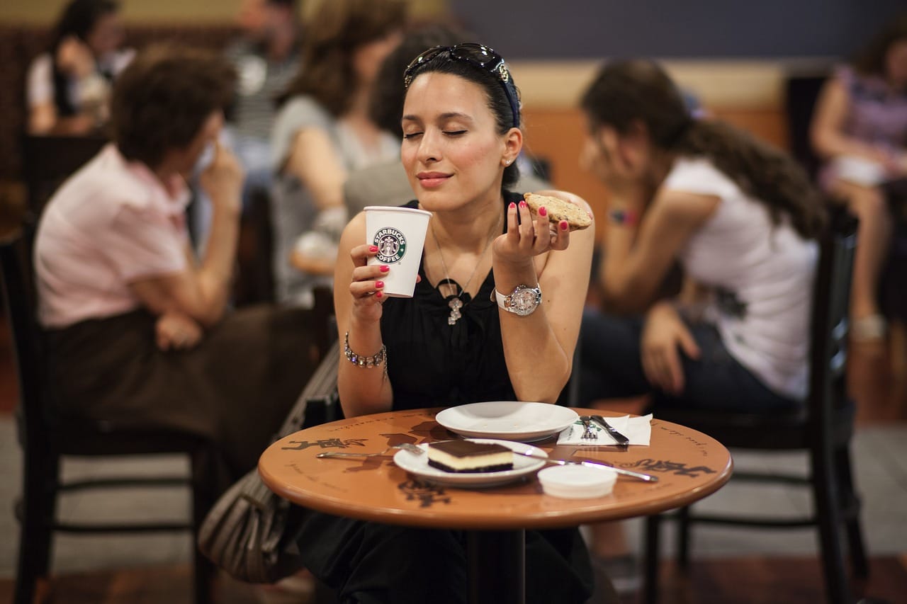 A woman drinking from a Starbucks cup.