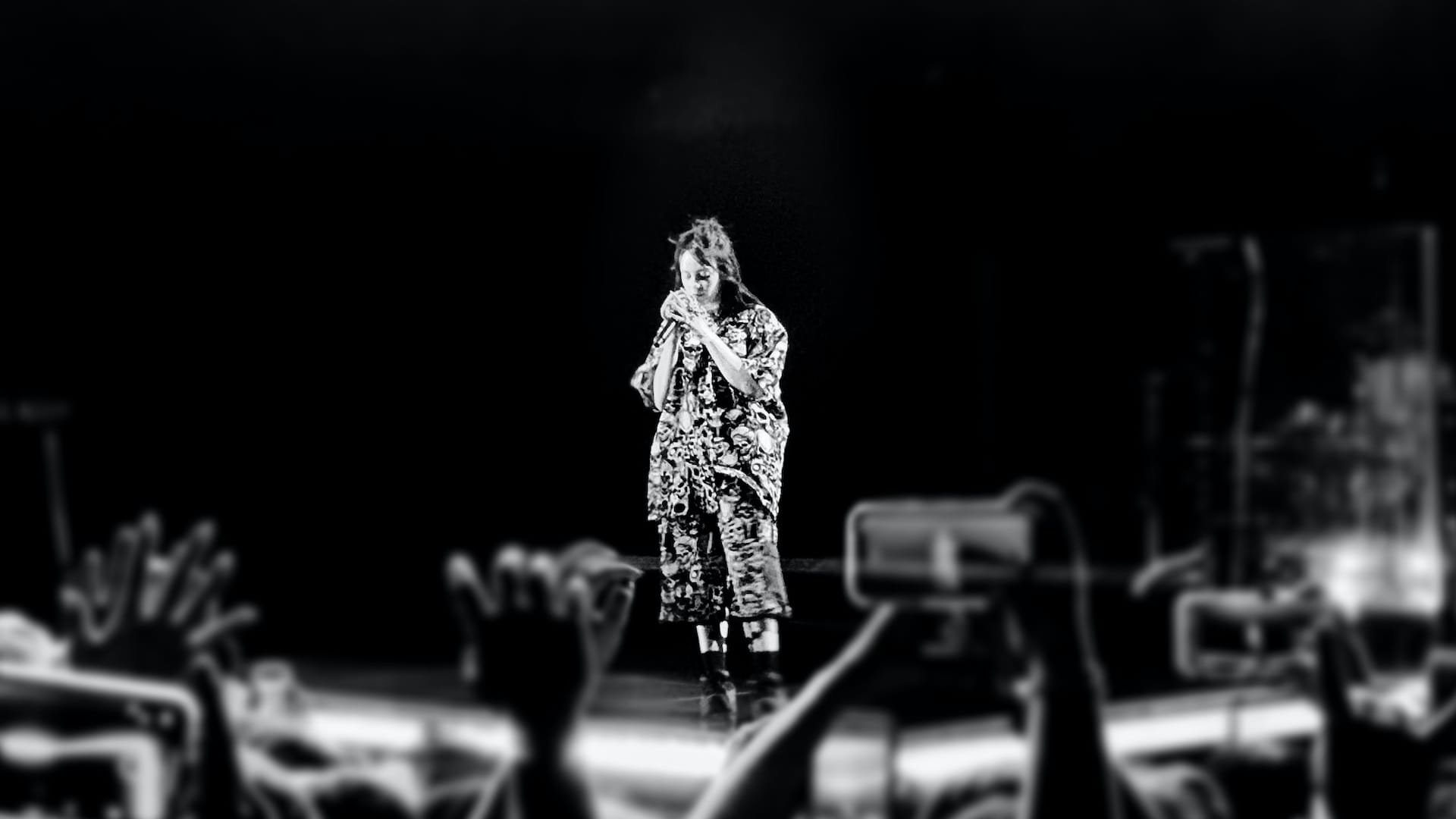 Billie Eilish at a concert, seen from afar.