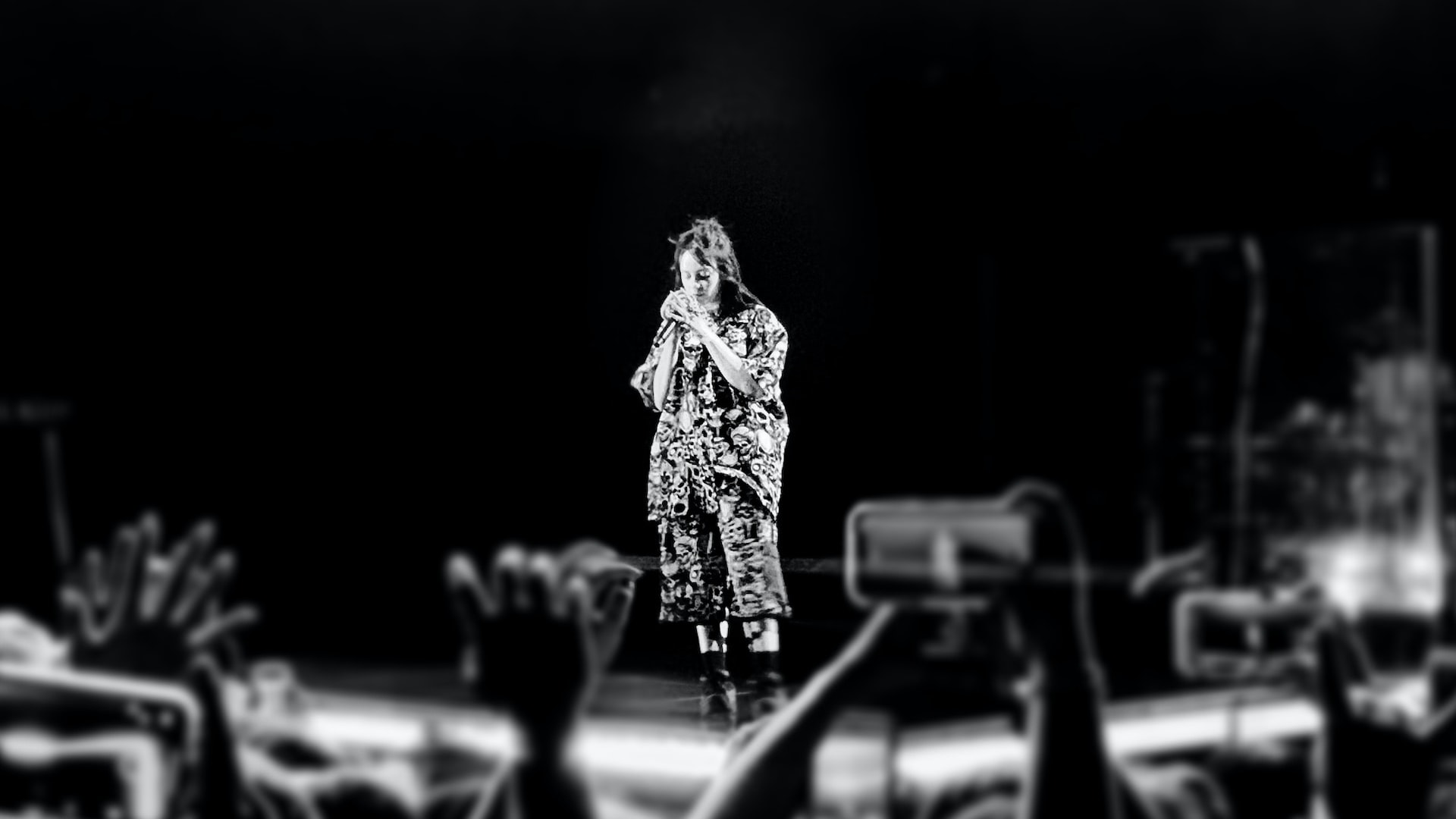 Billie Eilish at a concert, seen from afar.