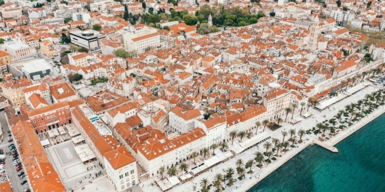 White buildings with orange roofs sit alongside the coast in Split, Croatia.