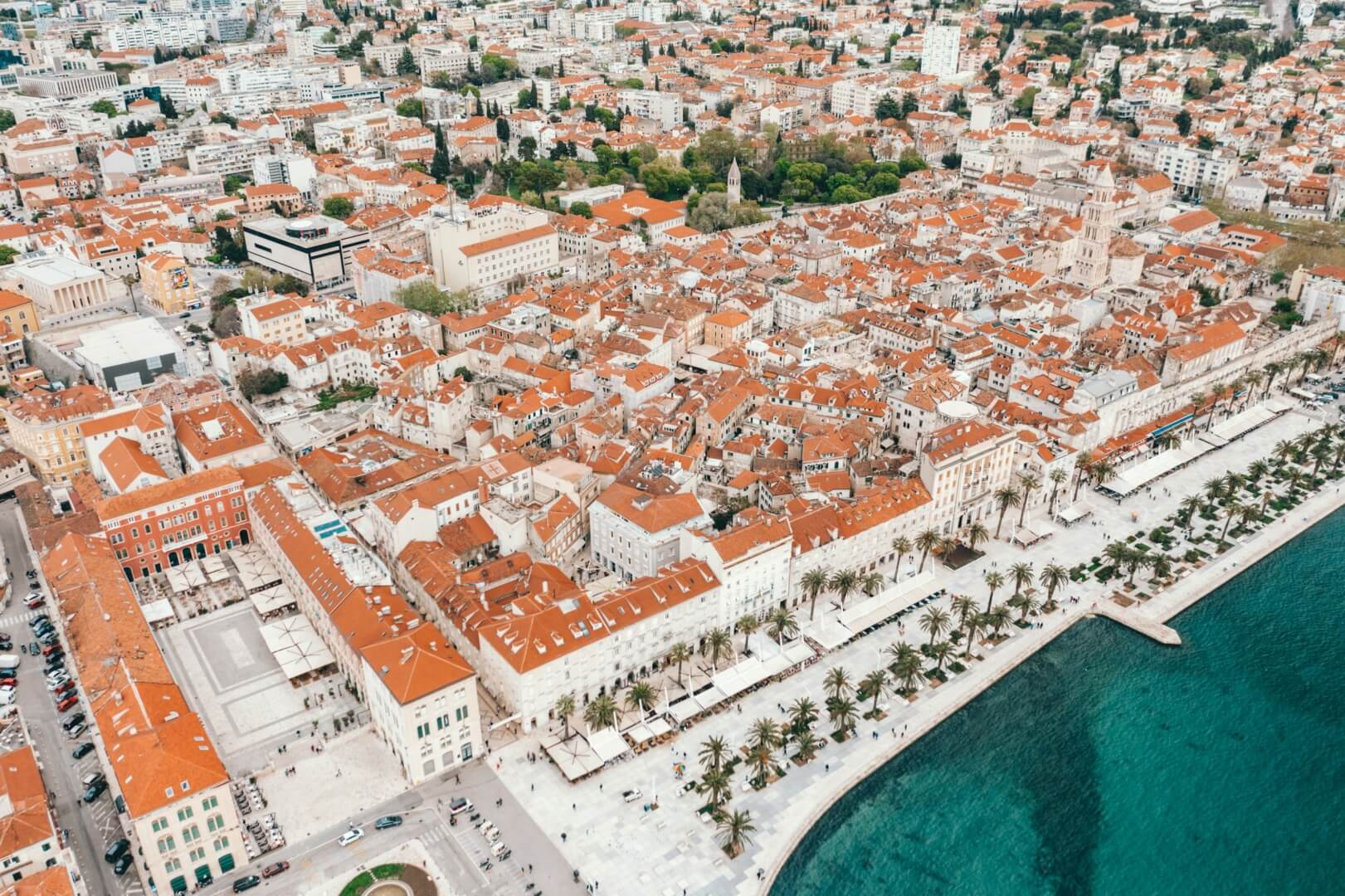 White buildings with orange roofs sit alongside the coast in Split, Croatia.