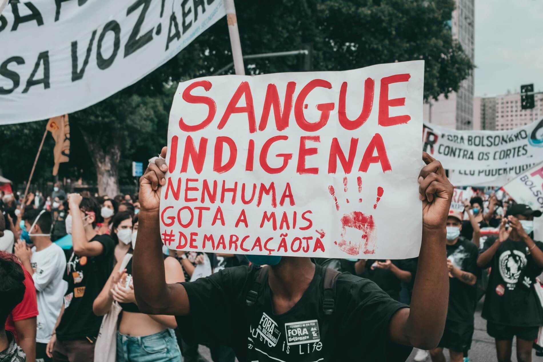 A man holds a sign in Portuguese at a protest in Brazil.