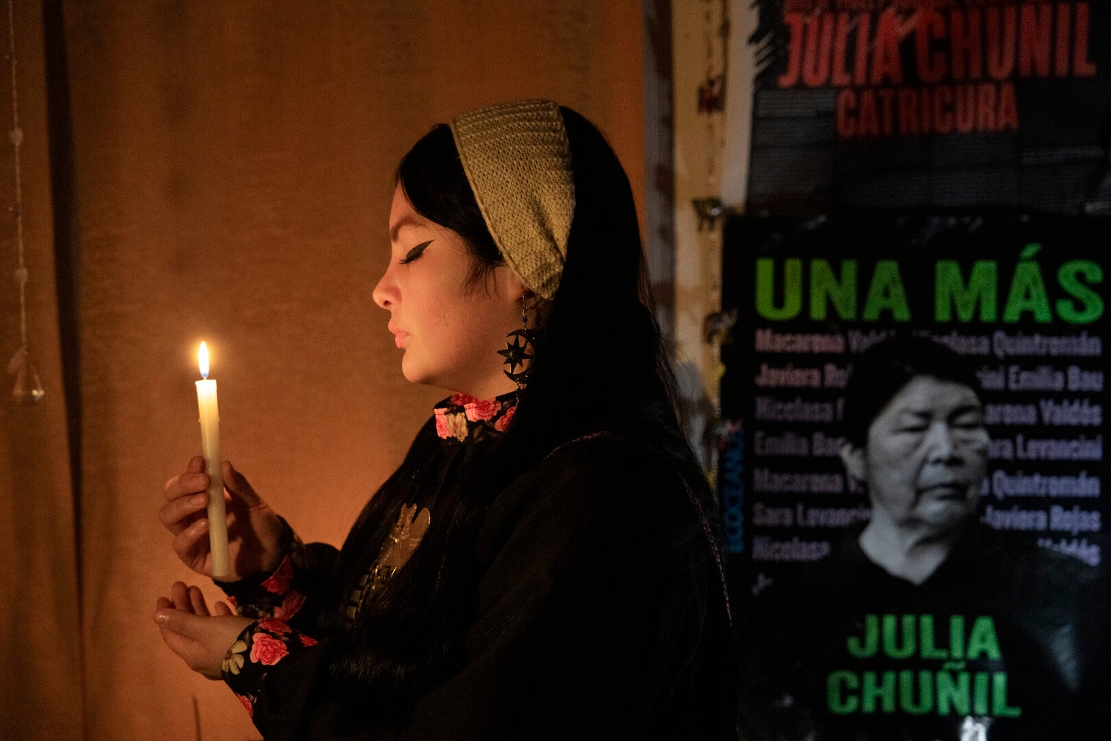 A solemn woman holds a lighted candle.