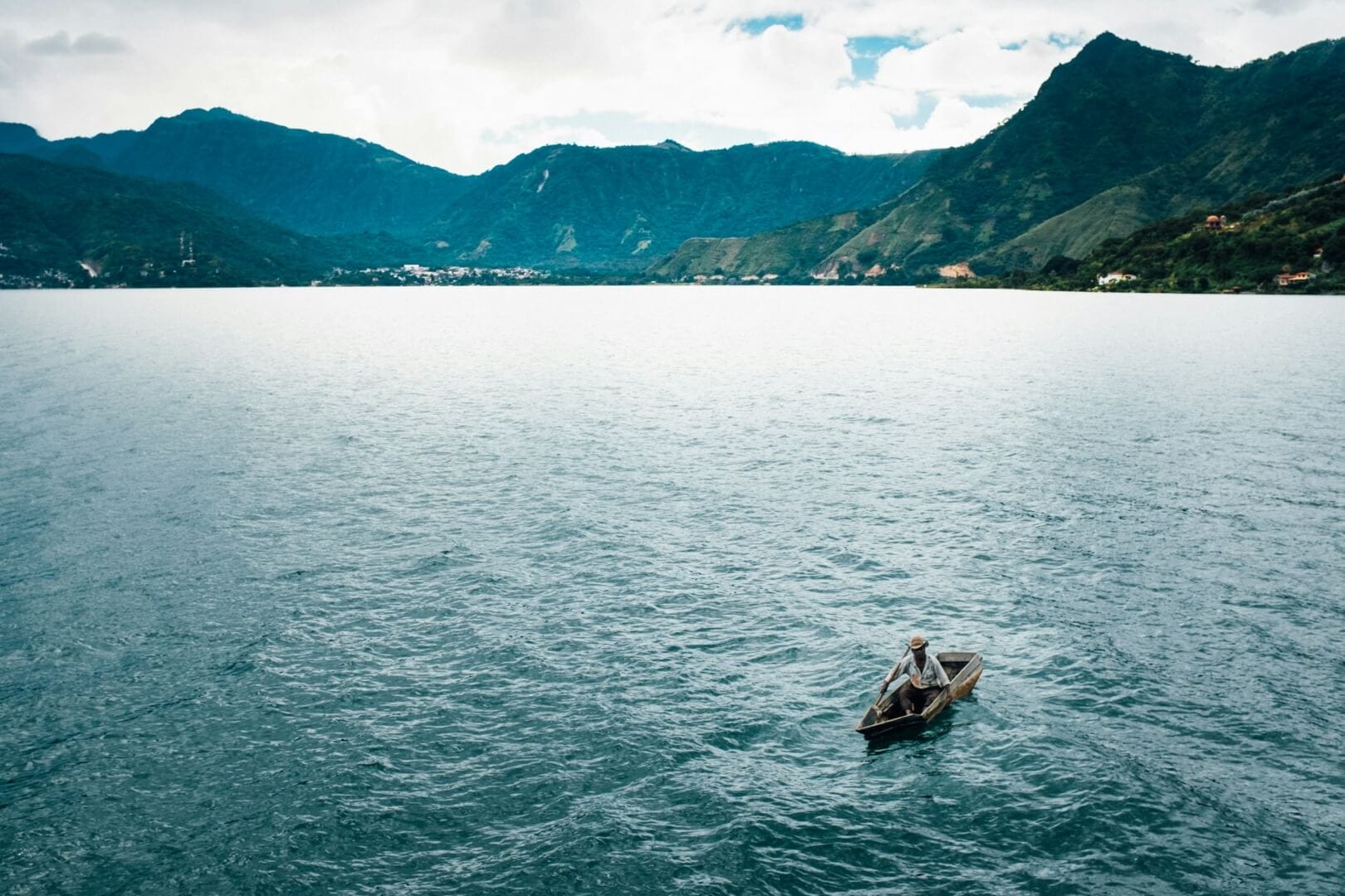 A fisherman paddles a canoe on a massive lake.