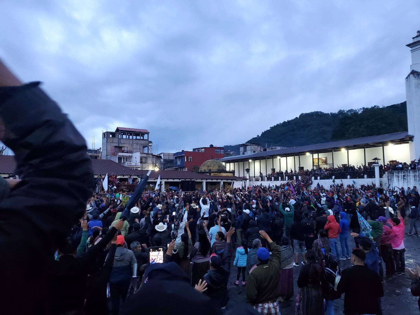 Attendees at a political rally raise their arms in the air.