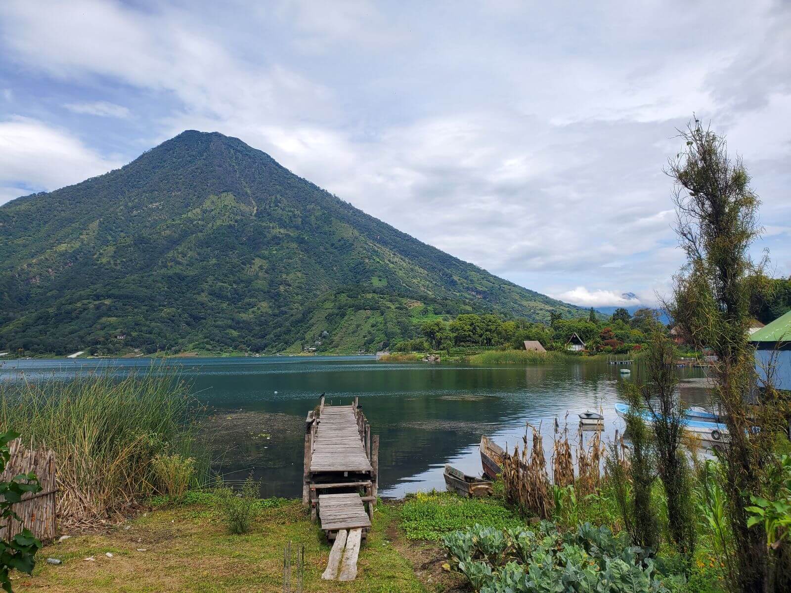 A dock extends into a lake with a volcano in the background.