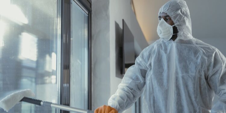 Industrial Hygiene carried by a A Man in a Coverall Suit Cleaning a Window
