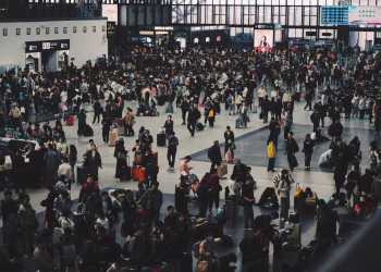 A crowded airport terminal with travelers moving through check-in areas during the holiday season.