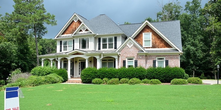 Home ownership: a beautiful country home with sales sign