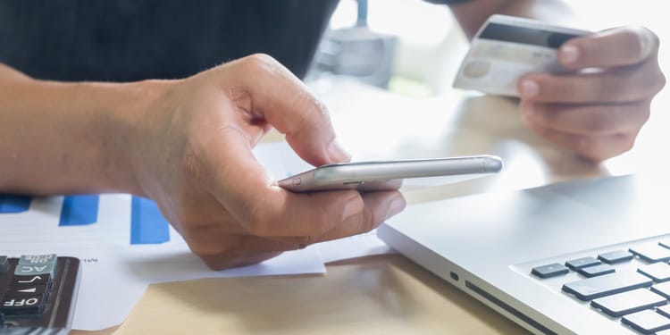 A man holding a phone and choosing which payments orchestration platform he should be using.