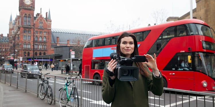 Content production in London - Woman standing with a camera in front of Westminster.