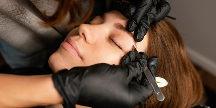 Eyebrow design: high-angle female beautician doing eyebrow treatment woman in Dubai