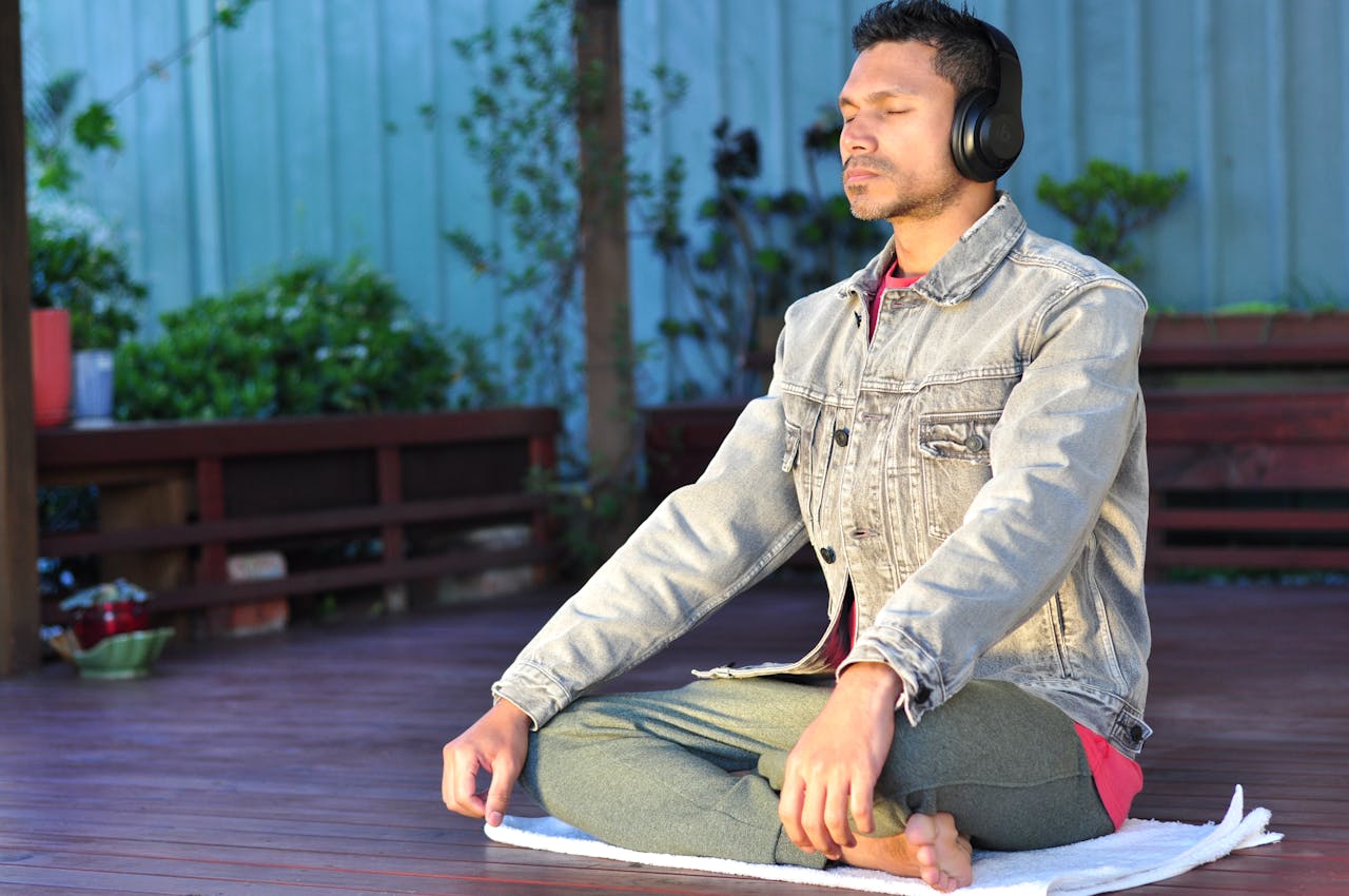 A man sitting on his yoga mat, managing stress through meditation.